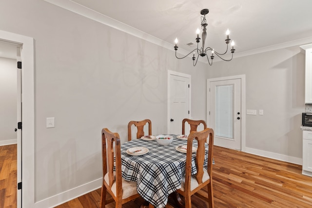 dining space featuring light hardwood / wood-style flooring, a notable chandelier, and ornamental molding