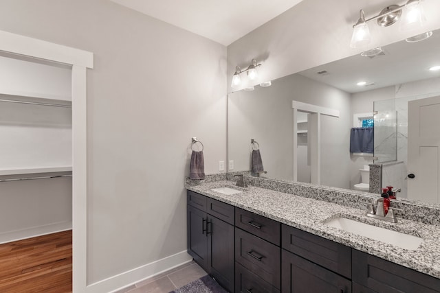 bathroom with a shower, vanity, hardwood / wood-style flooring, and toilet