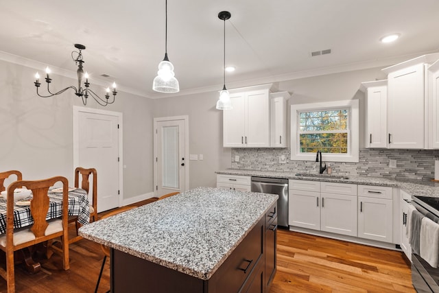 kitchen with a center island, sink, hanging light fixtures, appliances with stainless steel finishes, and white cabinetry