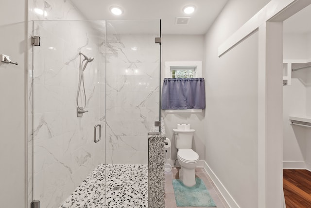 bathroom with hardwood / wood-style floors, toilet, and a shower with shower door