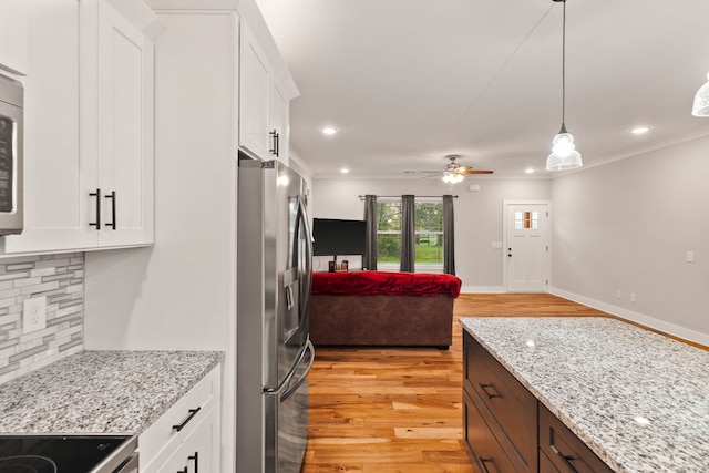 kitchen featuring decorative backsplash, appliances with stainless steel finishes, light wood-type flooring, decorative light fixtures, and white cabinets