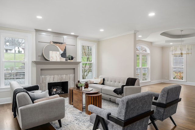 living room featuring a wealth of natural light, light hardwood / wood-style flooring, crown molding, and a notable chandelier