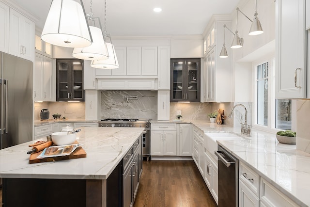 kitchen with sink, pendant lighting, high quality appliances, white cabinets, and a kitchen island