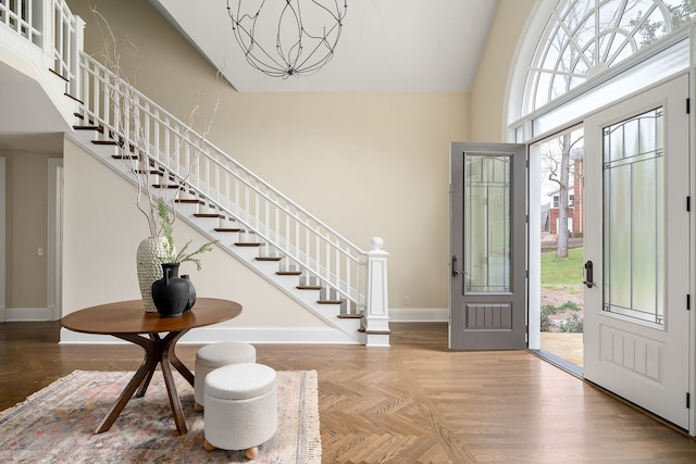 entryway featuring parquet flooring, a towering ceiling, and a notable chandelier