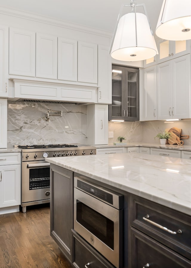 kitchen featuring dark wood-type flooring, tasteful backsplash, decorative light fixtures, white cabinetry, and stainless steel appliances