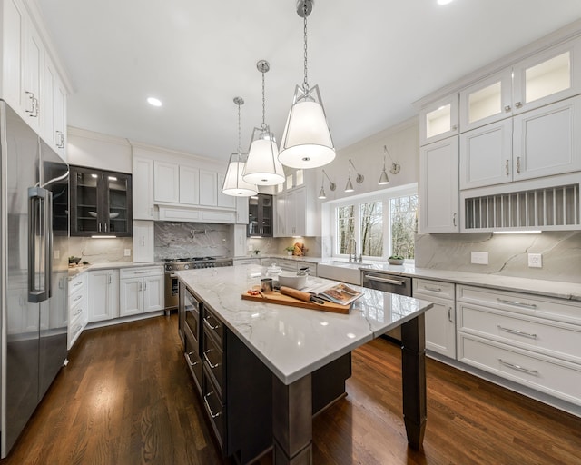 kitchen featuring premium appliances, a kitchen island, and white cabinetry