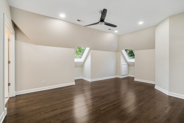 additional living space with ceiling fan, dark hardwood / wood-style flooring, and lofted ceiling with skylight