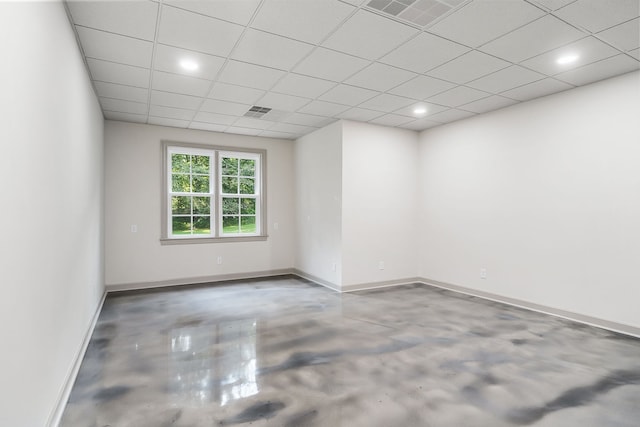 spare room featuring concrete floors and a drop ceiling