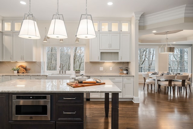 kitchen with white cabinets, a center island, a healthy amount of sunlight, and stainless steel oven