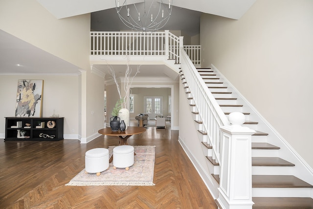 entrance foyer with french doors, dark parquet floors, an inviting chandelier, and ornamental molding