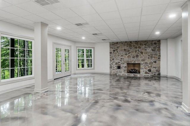 unfurnished living room featuring a fireplace, concrete floors, french doors, and a drop ceiling