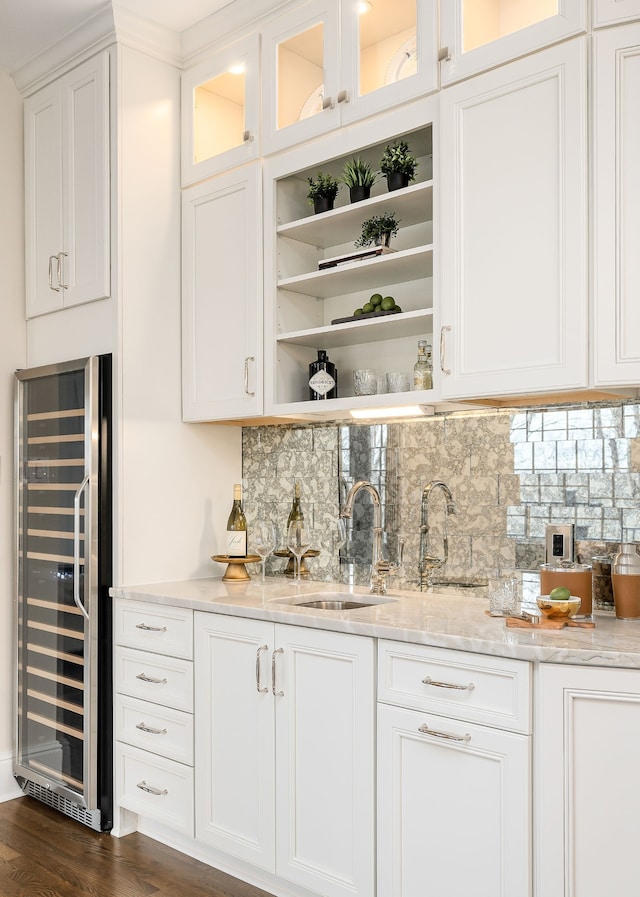 bar with sink, wine cooler, light stone counters, decorative backsplash, and white cabinets