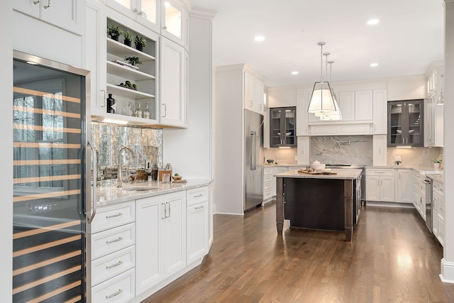 kitchen with dark wood-type flooring, high end refrigerator, sink, a kitchen island, and light stone counters