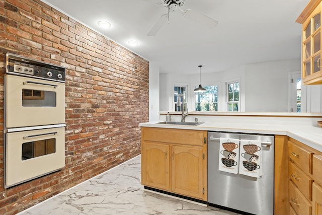 kitchen with dishwasher, sink, ceiling fan, double oven, and brick wall