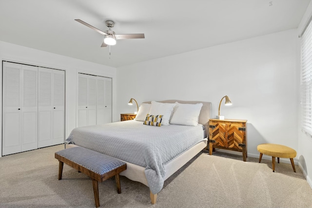 bedroom with ceiling fan, light carpet, and two closets