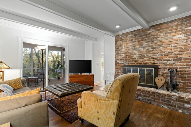 living room featuring ornamental molding, beamed ceiling, dark wood-type flooring, and a brick fireplace