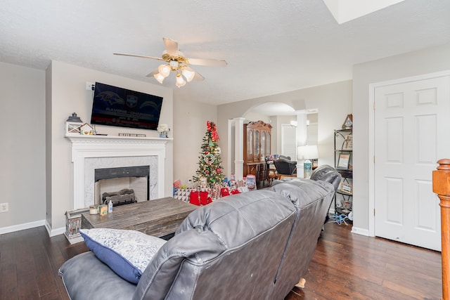 living room featuring ceiling fan, a high end fireplace, dark wood-type flooring, and a textured ceiling