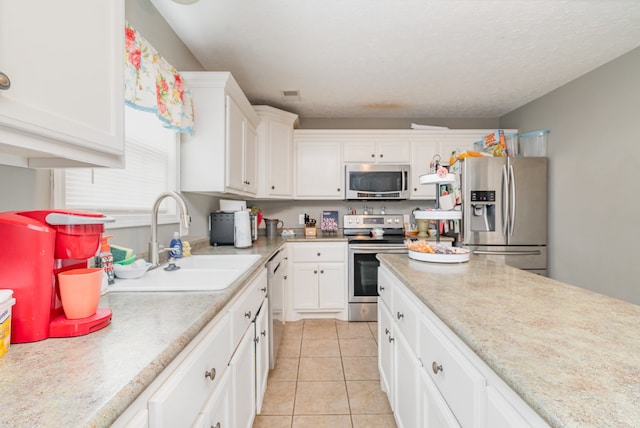 kitchen featuring sink, white cabinets, light tile patterned floors, and appliances with stainless steel finishes