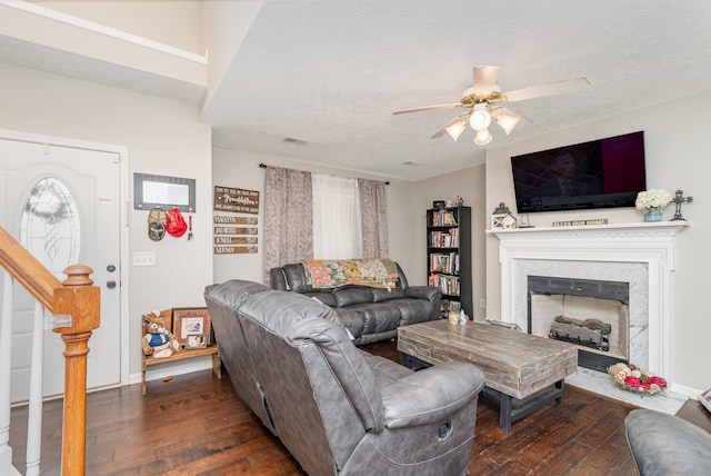 living room with a high end fireplace, a textured ceiling, dark hardwood / wood-style floors, and ceiling fan