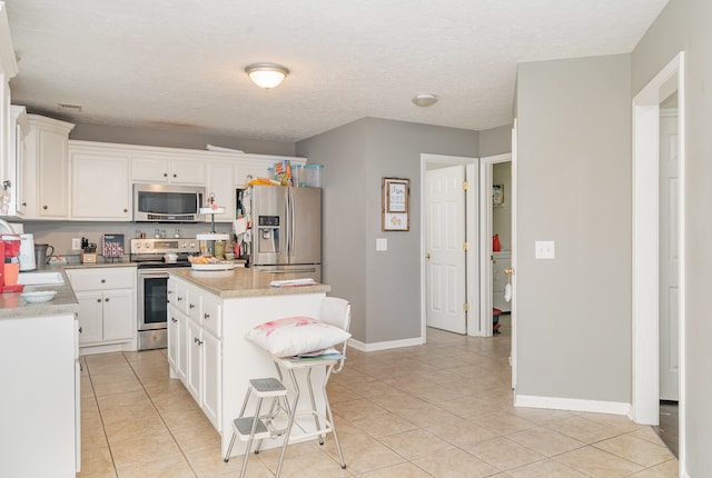 kitchen featuring white cabinets, sink, light tile patterned floors, a kitchen island, and stainless steel appliances