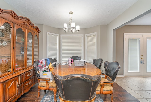 dining room with dark hardwood / wood-style floors, french doors, a textured ceiling, and a chandelier