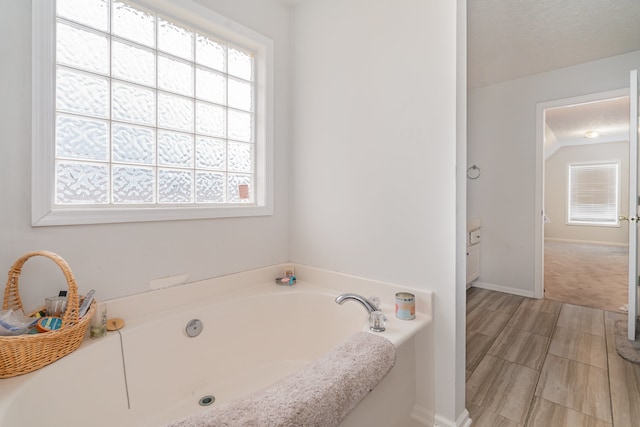 bathroom featuring vanity, a textured ceiling, and a tub