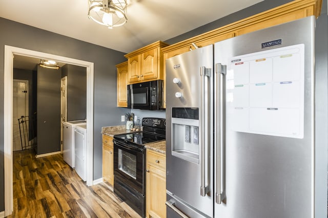 kitchen featuring light stone countertops, dark wood-type flooring, an inviting chandelier, independent washer and dryer, and black appliances