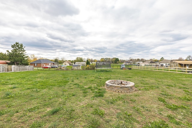 view of yard with a fire pit and a trampoline