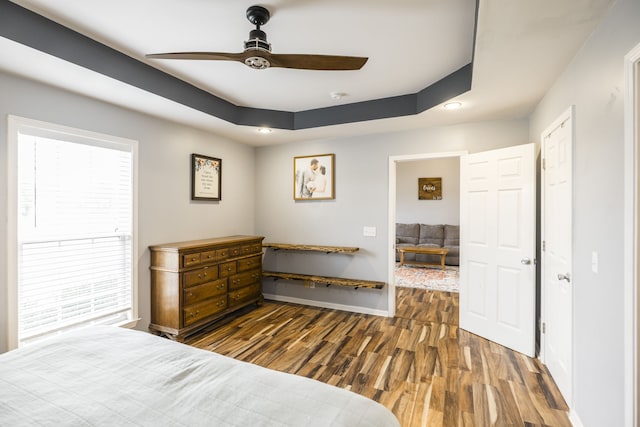 bedroom featuring dark hardwood / wood-style floors, ceiling fan, and a raised ceiling