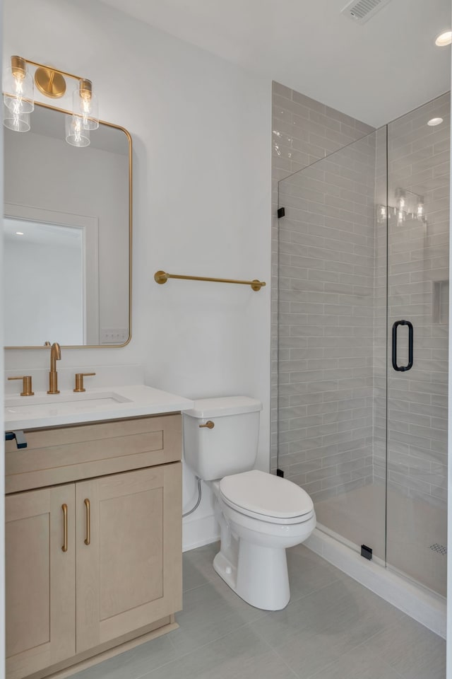 bathroom with tile patterned floors, a shower with door, vanity, and toilet