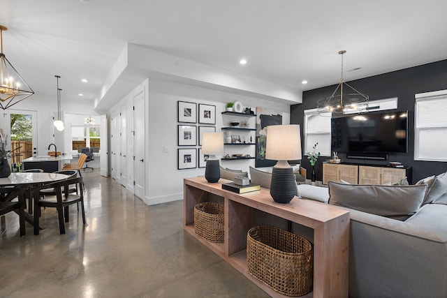 living room with concrete flooring and a notable chandelier