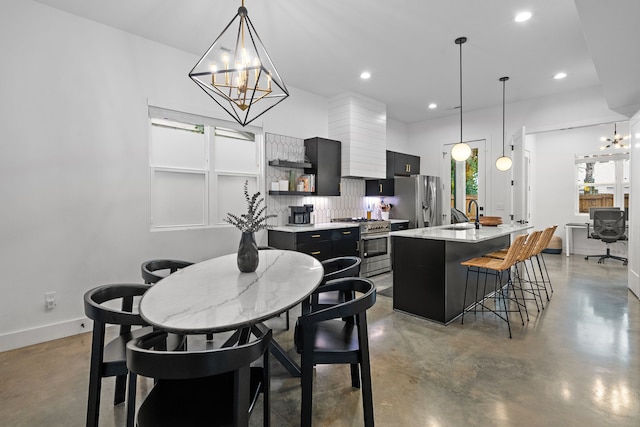 kitchen featuring a kitchen bar, appliances with stainless steel finishes, sink, hanging light fixtures, and an island with sink