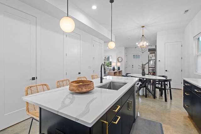 kitchen with sink, a center island with sink, a chandelier, hanging light fixtures, and a breakfast bar area