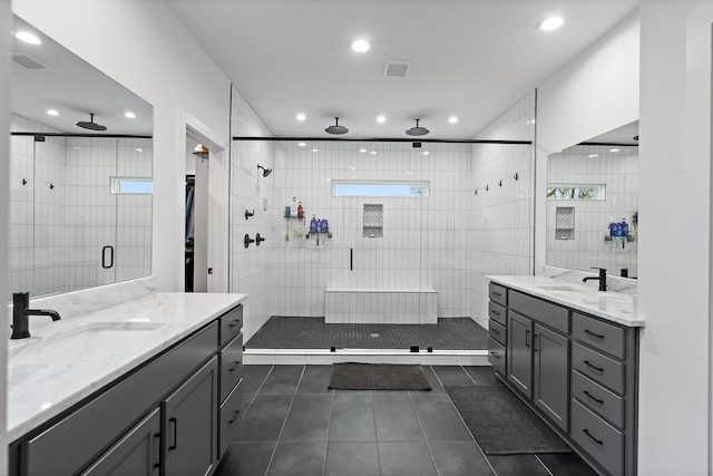 bathroom with tile patterned flooring, vanity, an enclosed shower, and tile walls