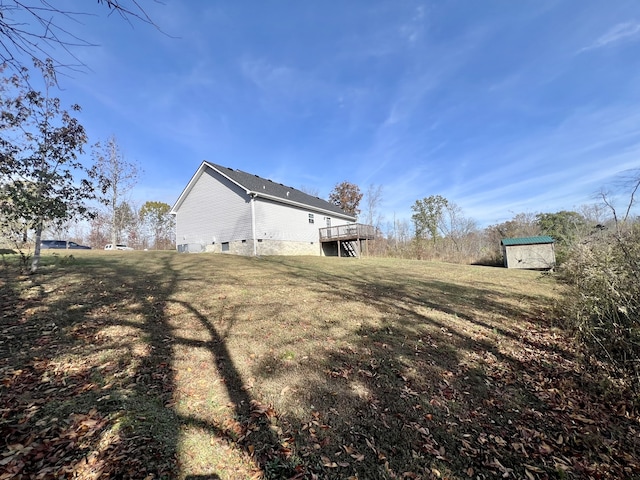 view of home's exterior featuring a wooden deck, a yard, and a storage unit