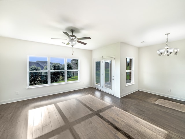 spare room with ceiling fan with notable chandelier, dark hardwood / wood-style flooring, and a wealth of natural light