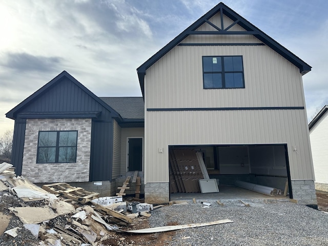 modern inspired farmhouse with a shingled roof, gravel driveway, and an attached garage