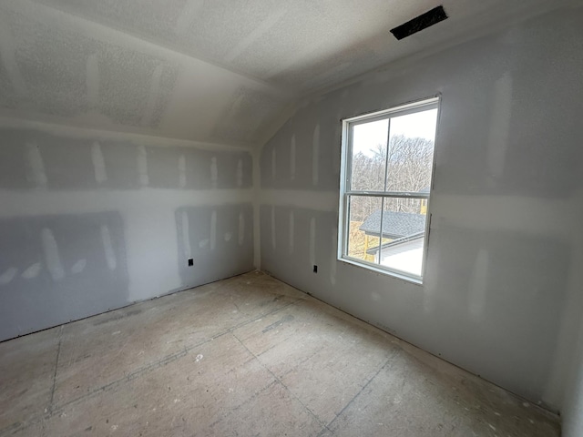 additional living space with vaulted ceiling and a textured ceiling