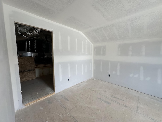 empty room featuring vaulted ceiling and a textured ceiling