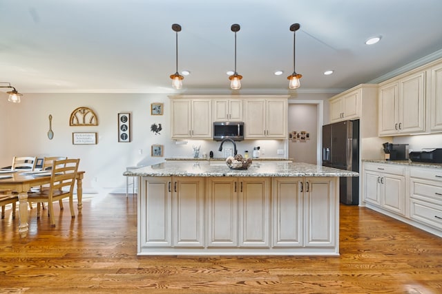 kitchen featuring pendant lighting, light hardwood / wood-style floors, an island with sink, and black refrigerator with ice dispenser