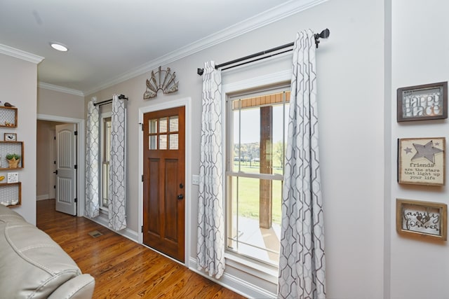 entryway with wood-type flooring, a wealth of natural light, and ornamental molding