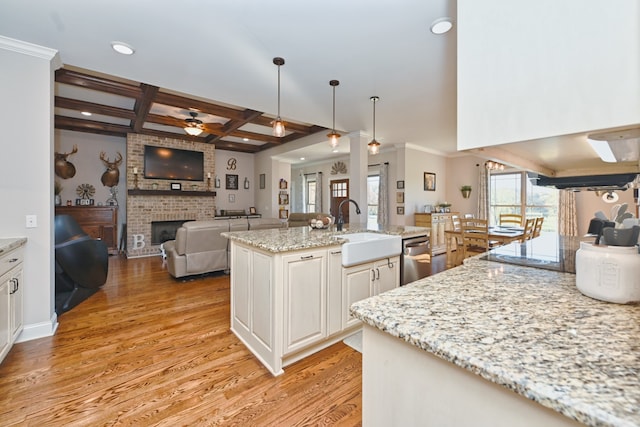 kitchen with coffered ceiling, ceiling fan, sink, and light hardwood / wood-style flooring