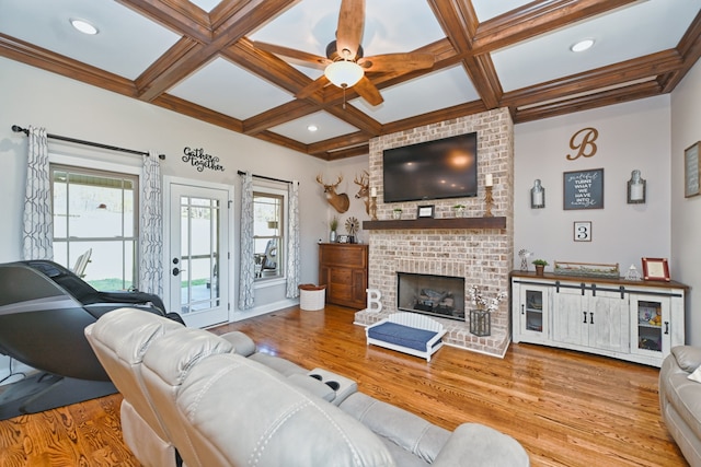 living room with a brick fireplace, coffered ceiling, ceiling fan, beam ceiling, and light hardwood / wood-style flooring