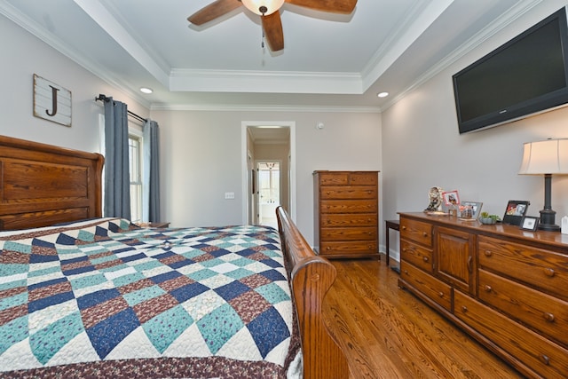 bedroom featuring dark hardwood / wood-style flooring, a raised ceiling, ceiling fan, and crown molding