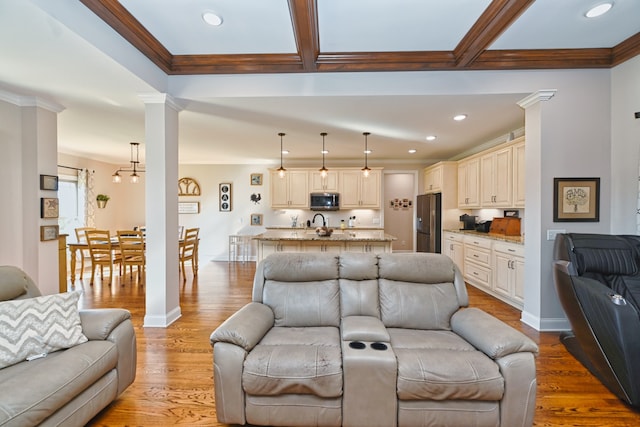 living room featuring beamed ceiling, ornate columns, ornamental molding, and light hardwood / wood-style flooring