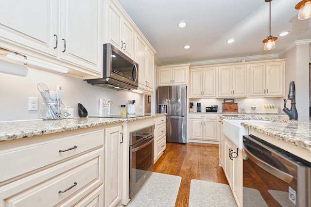 kitchen with pendant lighting, crown molding, light stone countertops, light hardwood / wood-style floors, and stainless steel appliances