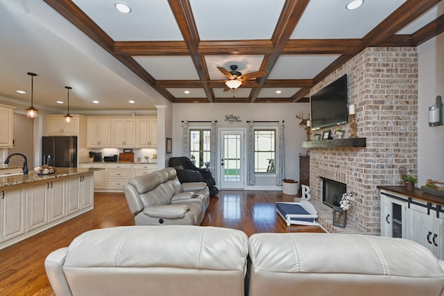 living room with beam ceiling, a fireplace, light hardwood / wood-style floors, and coffered ceiling