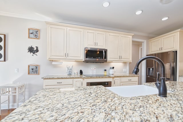 kitchen with ornamental molding, stainless steel appliances, sink, cream cabinets, and hardwood / wood-style flooring