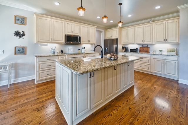 kitchen featuring pendant lighting, stainless steel appliances, a kitchen island with sink, and wood-type flooring