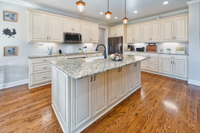 kitchen featuring sink, decorative light fixtures, a center island with sink, appliances with stainless steel finishes, and light wood-type flooring